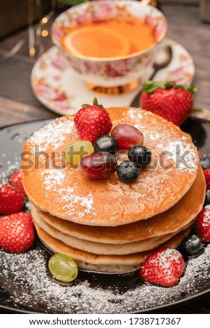 Fresh pancakes with fruit and icing sugar