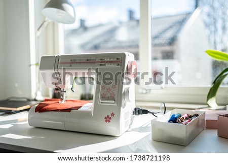 Sewing machine on the white table in fron of the window
