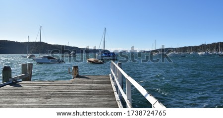 Taylors Point wharf (Clareville, NSW, Australia) in Pittwater bay in windy cold day wintertime. Some boats and yachts in the background. 