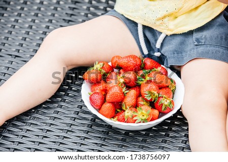 Homegrown organic strawberry. Child eating delicios seasonal strawberry at backyard. Summer holidays. Happy days. Spring time. Family vacation. Stress free life. Healthy snack. Balanced diet,