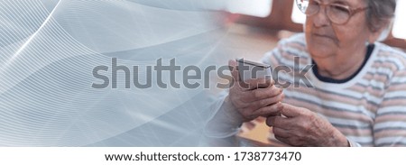 Elderly woman using a mobile phone; panoramic banner