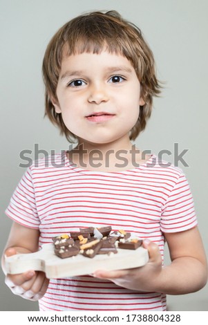 Happy girl kid holds pieces of chocolate and wants to eat sweet dessert