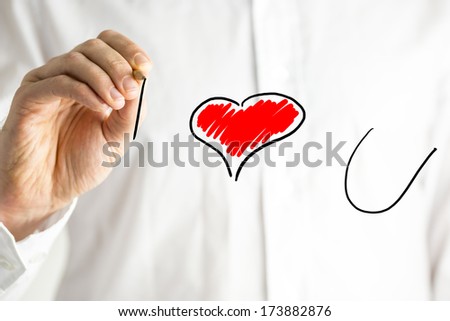 Man writing I Love You on a virtual screen with a red heart symbolising the word love as he declares his feelings for a loved one or sweetheart on Valentines Day or a special occasion