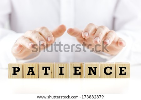 Conceptual image with the word Patience on wooden blocks or cubes protected by the hands of a man sheltering them from above Royalty-Free Stock Photo #173882879