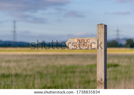 Directional wooden sign post with public footpath written on it.