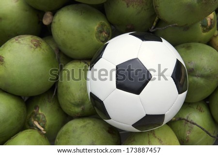 Soccer ball football resting on a pile of fresh green drinking coconut coco gelado in Rio de Janeiro Brazil