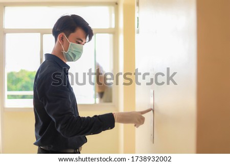 Men wear medical masks and medical gloves. Standing pressing lift button. Male office worker waiting for elevator in modern office building. Royalty-Free Stock Photo #1738932002