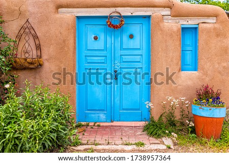 New Mexico traditional colorful architecture with blue turquoise adobe color painted door and ristras decorations at entrance garden Royalty-Free Stock Photo #1738957364