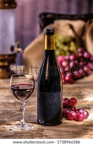 Ripe grapes red wine glass and bottle of wine on a wooden background