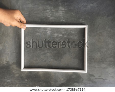 White frame isolated on grey background. Hand, frame and cement
