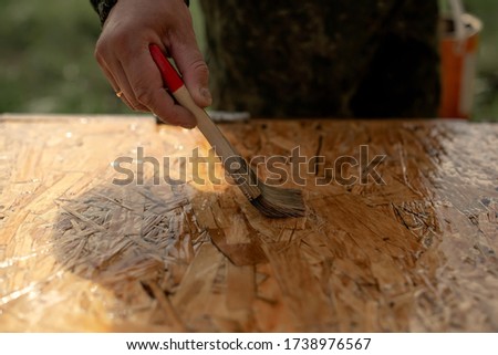 a man paints a Board with a brush. Wood coating with varnish
