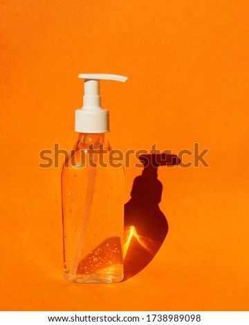 Bottle with gel hand sanitizer. Orange colorful background. Means of hand disinfection during a pandemic Coronavirus