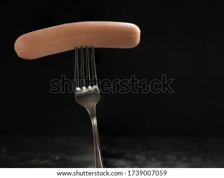 Sausage on a fork on a black background