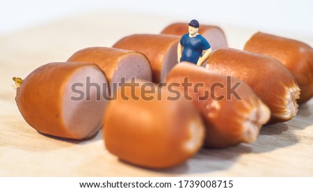 Miniature people : Close up fat man standing with sausages isolated on white background 