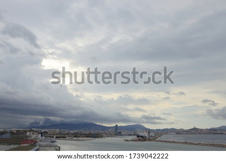 Dramatic grey sky with thunder clouds above the sea cost line near Marseille with old town far on horizon, France
