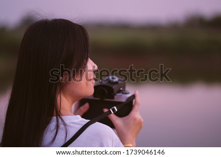Portrait of beautiful smile asian woman with holding medium format film camera with green nature background