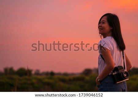 Portrait of beautiful smiling asian woman with holding medium format film camera with colorful sunset sky background