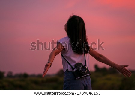 Portrait of beautiful freedom asian woman with holding medium format film camera with colorful sunset sky background