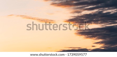 Sky at dawn. A magical, bright sky in orange sunlight and sparse, small, long clouds above the horizon.