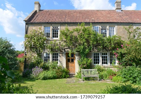 Exterior View and Garden Lawn of a Beautiful Old Rural English Cottage House Royalty-Free Stock Photo #1739079257