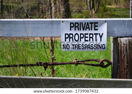 Sign on wooden fence stating Private Property No Trespassing. Close up.