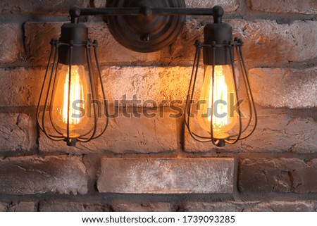 Two round glowing lamps on a gray brick wall. Retro interior design.