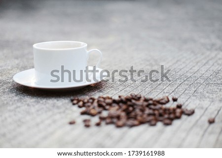 White ceramic cup of hot coffee and beans on concrete floor with natural light morning in the garden. Caffeine drinks cause a fresh feeling.