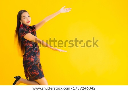 Portrait beautiful young asian woman wear chinese dress with action for chinese new year concept on yellow isolated background