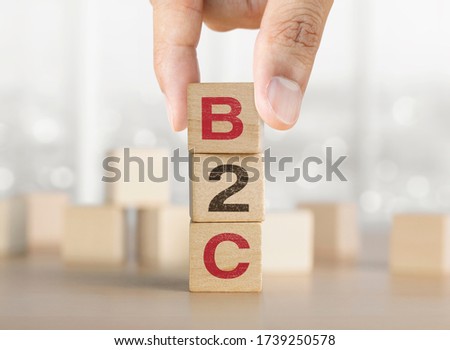 Hand arranging wooden blocks with the word B2C. Business to consumer marketing concept.