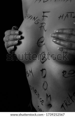 part of the body of a young girl with the inscription freedom . the captions are written in the photographer's hand, not in a tattoo . black and white photo.