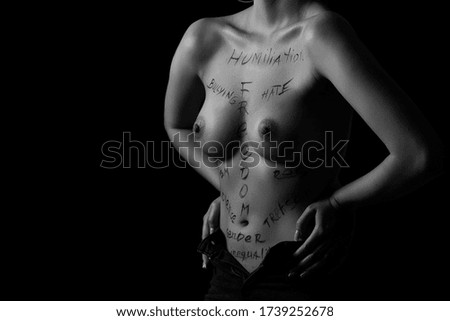 part of the body of a young girl with the inscription, humiliation, bullying, freedom . the captions are written in the photographer's hand, not in a tattoo . black and white photo