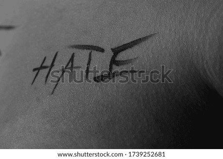 part of the body of a young girl with the inscription hate . the captions are written in the photographer's hand, not in a tattoo . black and white photo.