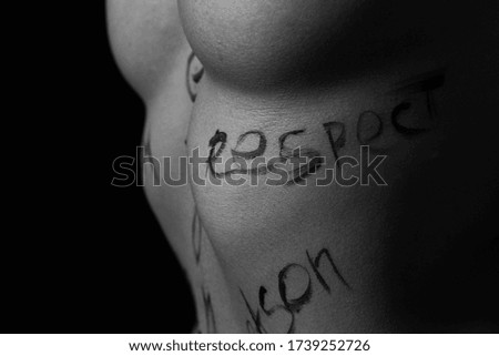 part of the body of a young girl with the inscription respect . the captions are written in the photographer's hand, not in a tattoo . black and white photo