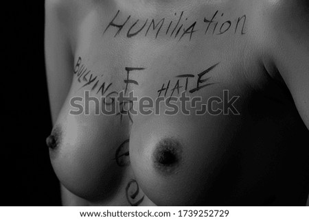 part of a young girl's body with the words freedom, hate, humiliation, bullying . the captions are written in the photographer's hand, not in a tattoo . black and white photo.