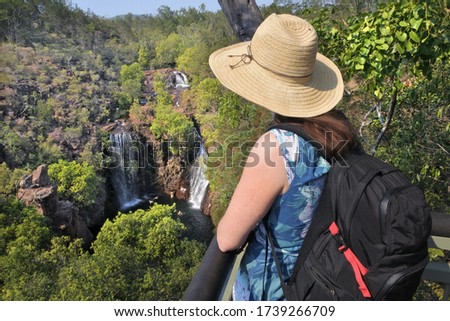 Young adult Australian woman tourist looking at landscape view of Lorence Falls in Litchfield National Park Northern Territory Australia. Real people. Copy space