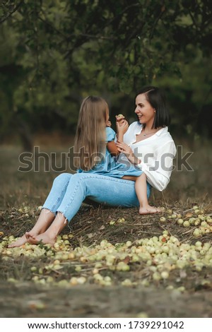 mom and daughter play in the apple garden