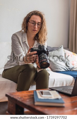 Smiling female photographer edits her photographs at home.
