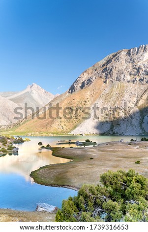 The Pamir range view and peaceful campsite on Kulikalon lake in Fann mountains in Tajikistan. Amasing colorful reflection in pure ice lake.