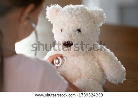 Close up of caring little girl kid listen to teddy bear heartbeat with statoscope, play doctor patient game at home, loving small child examine plush toy, do health checkup, healthcare concept