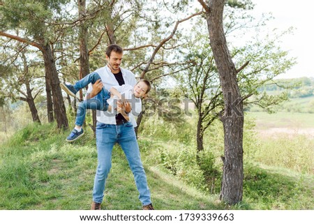 Handsome dad with his little cute son are having fun and playing on green grassy lawn. Happy family concept. Beauty nature scene with family outdoor lifestyle. family resting together. Fathers day