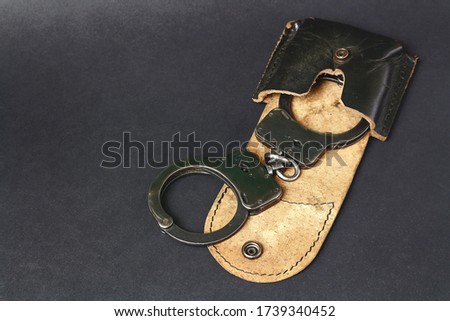 Handcuffs in a holster on a black background. 