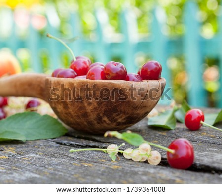 Red sour cherries in a wooden spoon, white currants and apples. Summer fruit. Healthy food.