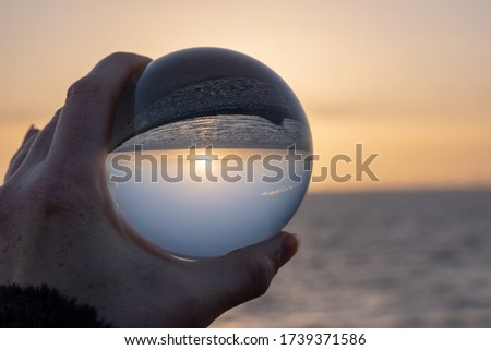Sunset over the sea seen through a glasball