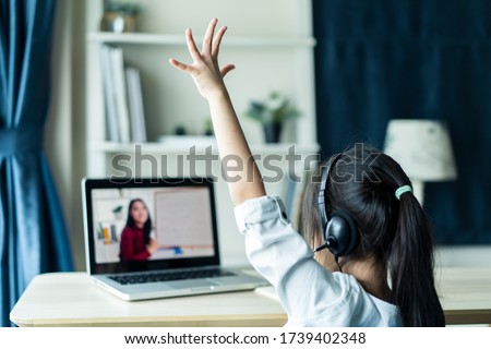 Homeschool Asian little young girl student learning virtual internet online class from school teacher by remote meeting due to covid pandemic. Female teaching math by using headphone and whiteboard. Royalty-Free Stock Photo #1739402348