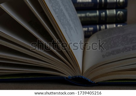An open book on a table in a dark library. Close-up of a hardback book in a library that is locked. Education, hobbies, knowledge. Focus in the foreground.