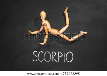 Wooden man depicts the zodiac sign Scorpio on a background of chalk board