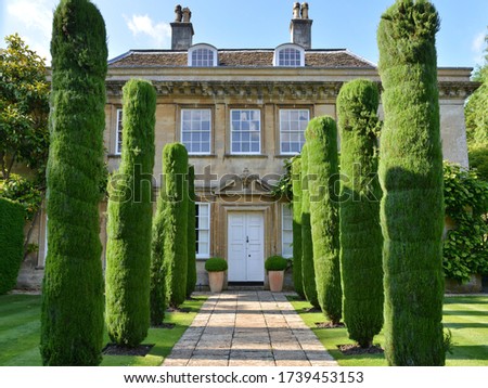 Tree Lined Garden Path Leading to an Old English Mansion Royalty-Free Stock Photo #1739453153
