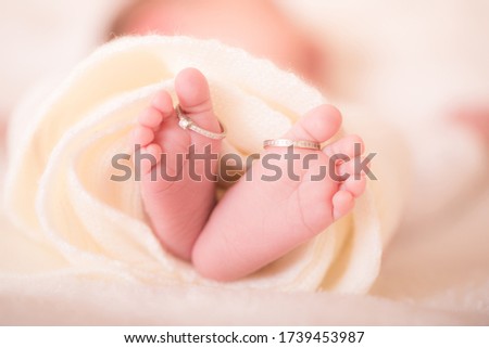 Legs of a newborn baby with mom's wedding ring in a warm white wool rug. Happy Family concept. Beautiful conceptual image of Maternity. Royalty-Free Stock Photo #1739453987