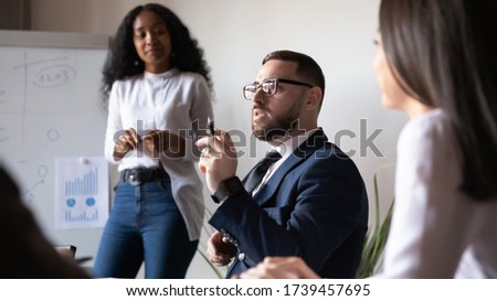 Confident businessman speaking at corporate meeting with business coach, sharing new startup ideas, discussing project strategy with partners, brainstorming with colleagues at briefing in boardroom Royalty-Free Stock Photo #1739457695