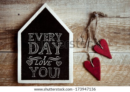 house shaped chalk board  "Every day I love you" with two red vintage hearts and rustic old wooden background